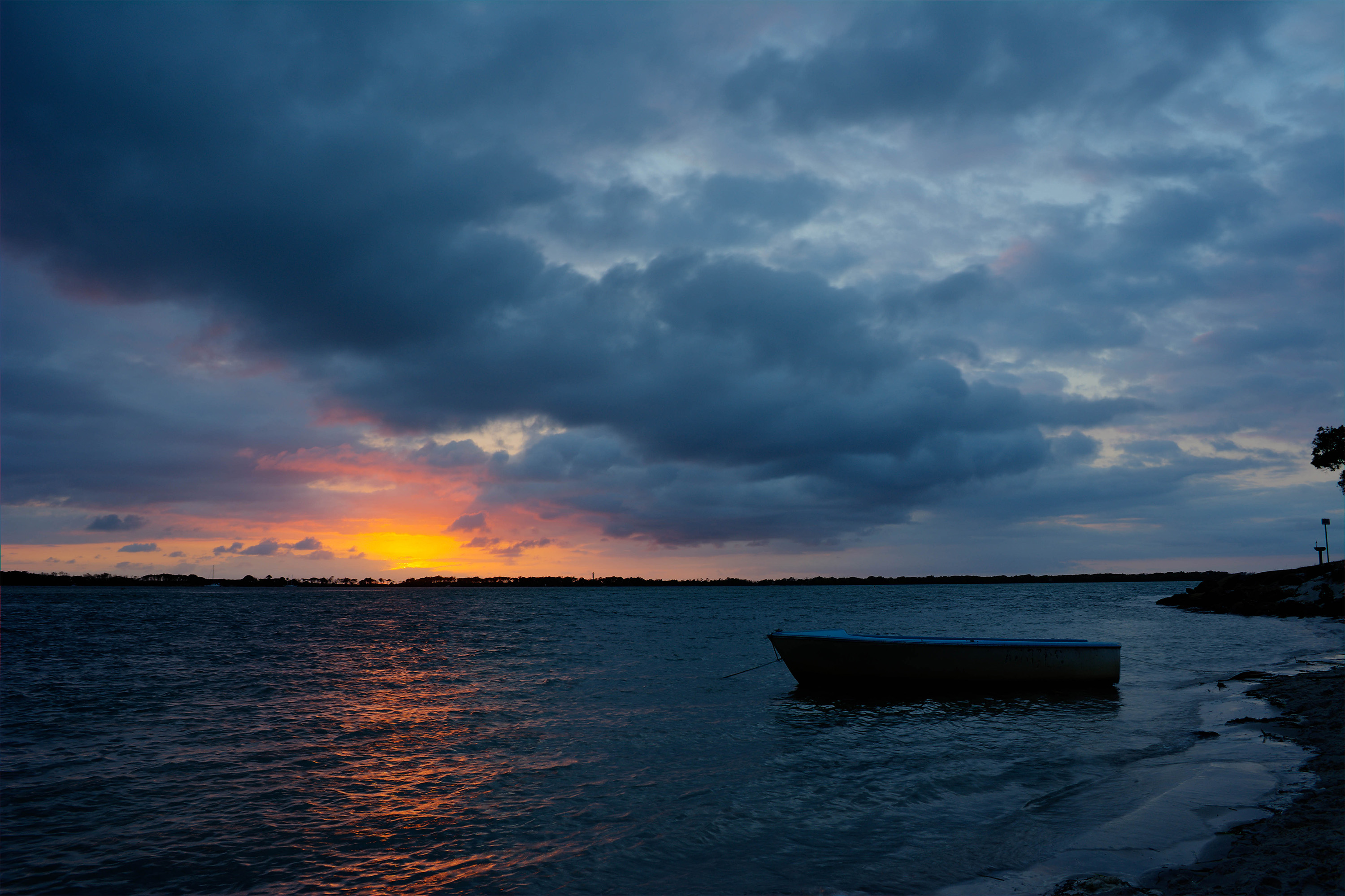 Sunrise with boat on water.