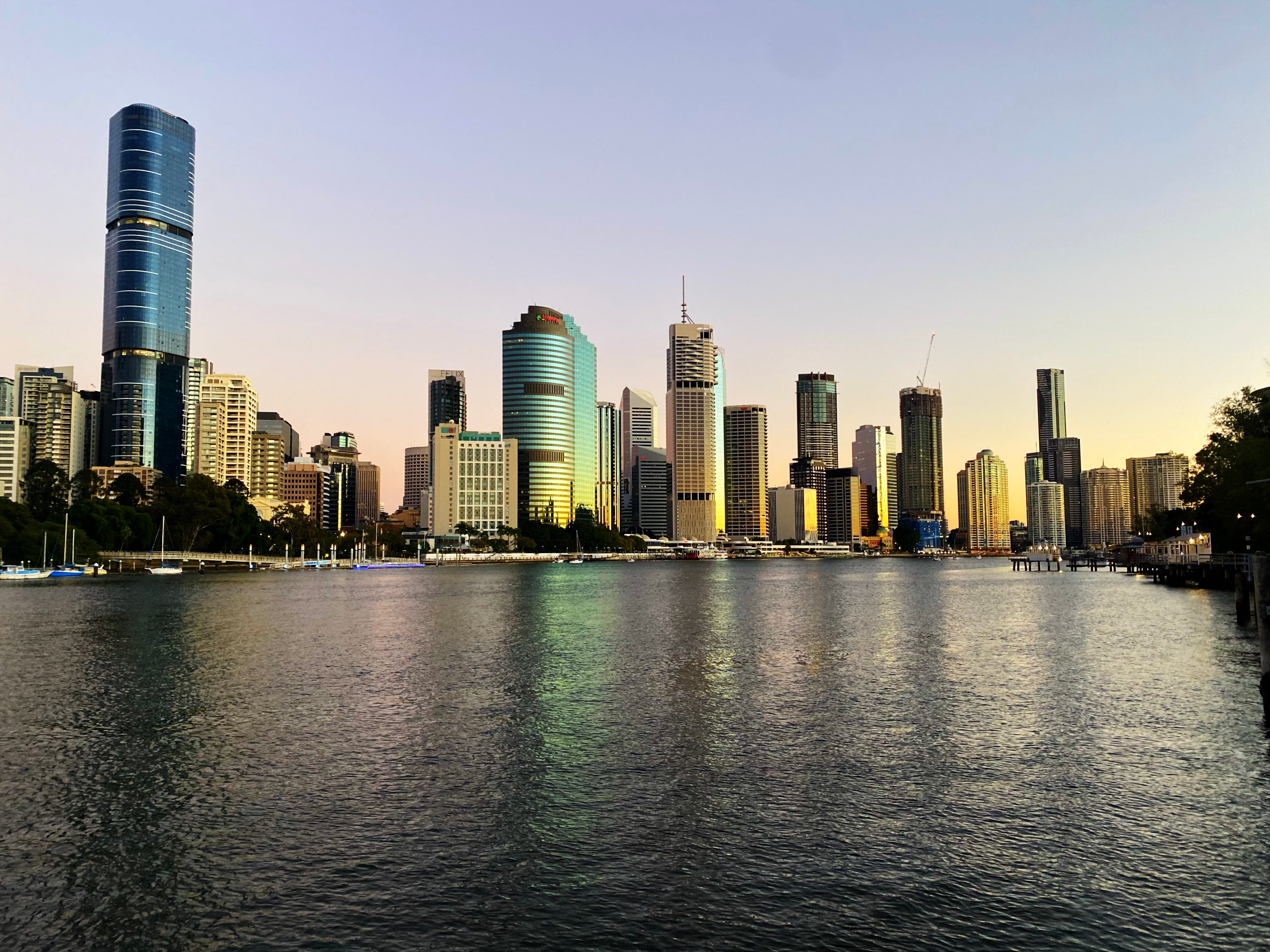 Sunrise reflecting in the windows of buildings over the Bisbane River. Brisbane, Queensland, Australia. 5 August 2021